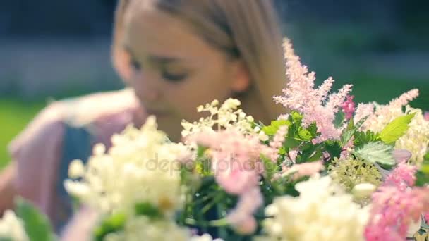 Молодая женщина позирует камера играет смотреть вниз камеру скрывается в цветах на изумрудно свежей траве снаружи — стоковое видео