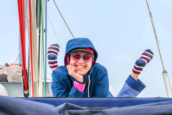 Happy, beautiful, young woman getting cold on a deck of yacht on the boat