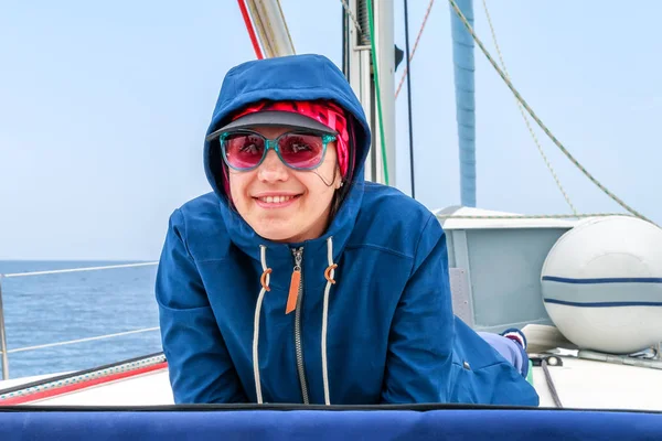 Happy, beautiful, young woman getting cold on a deck of yacht on the boat
