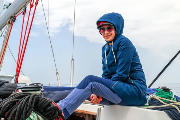 Young woman getting cold sailing the boat. Sitting on a deck of yacht.vzroslyiavantiuraprikliuchieniierisknutriskovatosienosienniikrasivieishiekrasivyipriekrasnyi