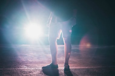 Geceleri bir adamın bacaklarının silueti spot ışıklarının ardında.