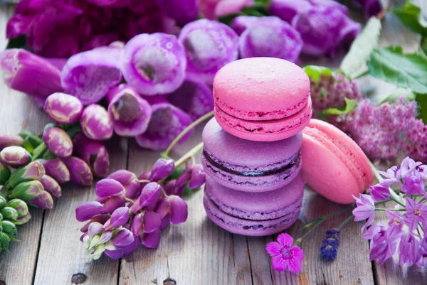 Purple and pink flowers and macaroon on a wooden background — Stock Photo, Image