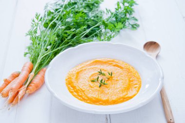 Beyaz ahşap zemin üzerinde krem havuç çorbası