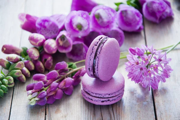 Fleurs violettes et macarons sur fond bois — Photo