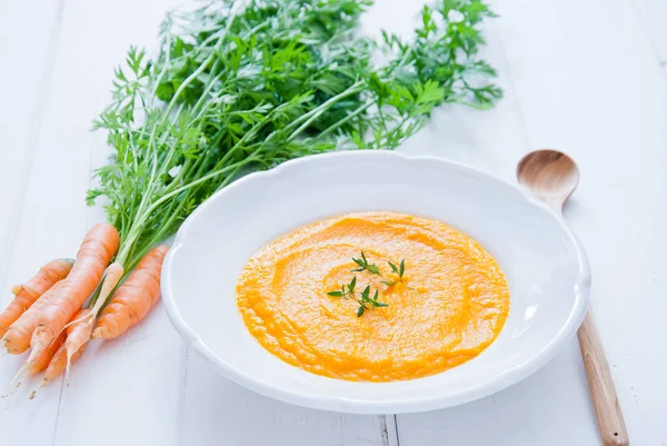 Creamy Carrot Soup on white wooden background Stock Photo