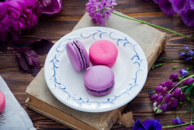 Mor ve pembe çeşitli çiçekler ve mor ve pembe badem kurabiyeleri.