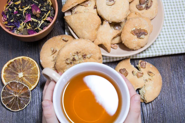 Bir daire ve bir fincan çay bir çocuğun elinde kurabiye dağılın