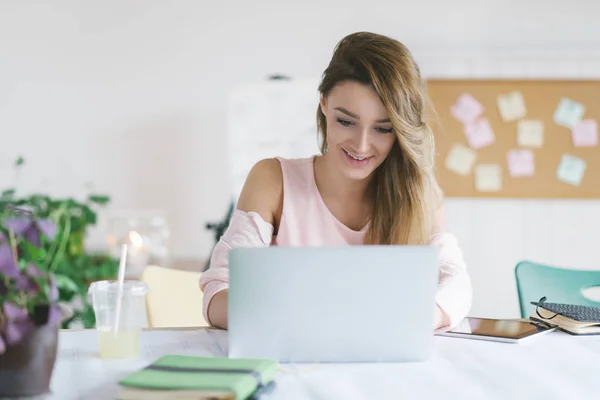 Joven mujer de negocios sonriente trabajando en su oficina y escribiendo en su computadora portátil ... —  Fotos de Stock