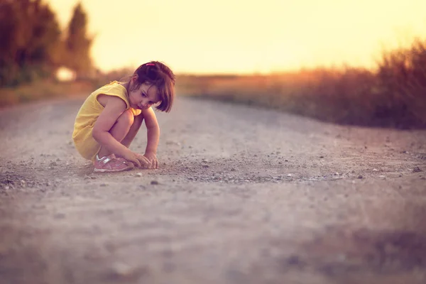 Cute little girl sitting on road — Stock Photo, Image