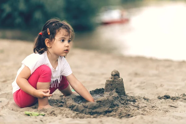 Söt liten flicka som leker på stranden Stockbild