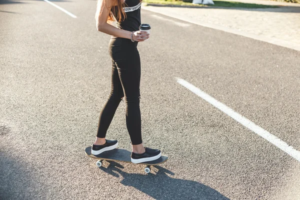 Sexy girl on a skateboard with cup of coffee — Stock Photo, Image