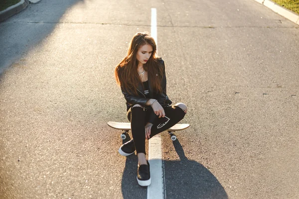 Schöne junge Frau posiert mit einem Skateboard — Stockfoto