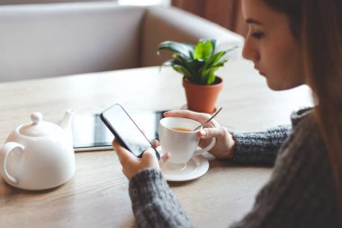 Genç kadın restoran ve Smartphone'da yazarak çay içmek