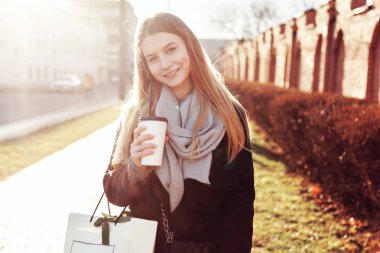 Alışveriş çantası sıcak içecek fincan holding ile güzel kız.