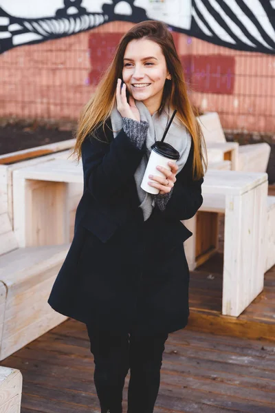 Feliz joven adolescente hablando por teléfono con una taza de café para llevar — Foto de Stock