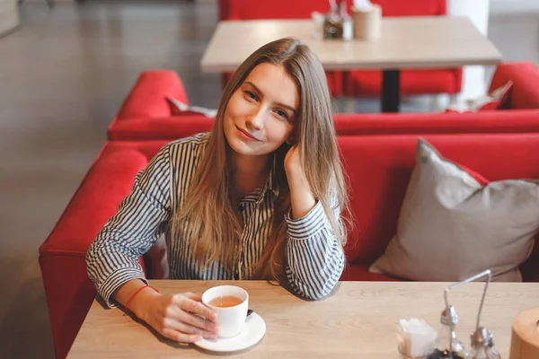 Молодая женщина пьет чай в кафе — стоковое фото