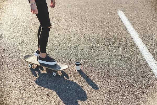 Zonsopgang skateboarden vrouw benen en koffie op het bord — Stockfoto