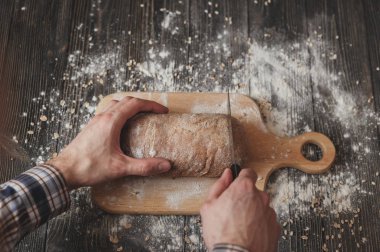 ahşap tahta üzerinde bıçak kesim ev pişmiş ekmek ile ekose gömlekli adam