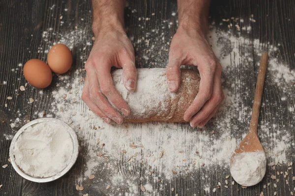 Närbild av mäns baker händer på svart bröd med mjöl pulver. Bakning och konditori koncept — Stockfoto