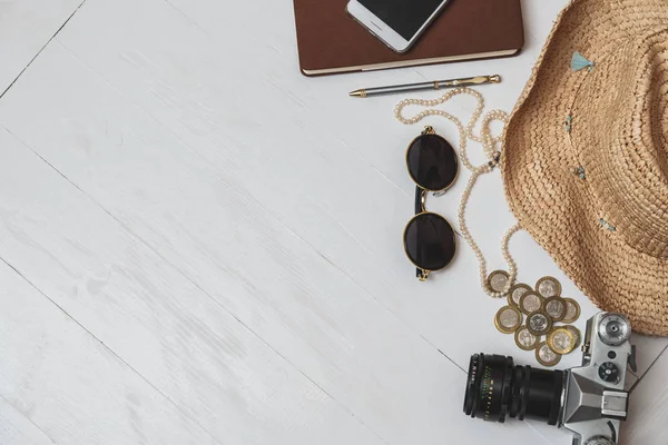 Pojęcie stylu kobiece podróży. Pieniądze, biżuteria, telefon, kapelusz, Okulary, aparat na białym tle drewnianych — Zdjęcie stockowe