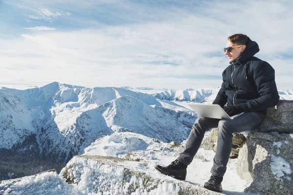 Giovane blogger o freelance che lavora su un computer portatile in cima al mondo. Paesaggio invernale nella giornata di sole . — Foto Stock