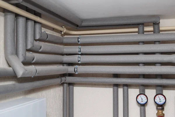 Las tuberías en el aislamiento y manómetros de flujo y tuberías de retorno en la sala de calderas de una casa privada —  Fotos de Stock