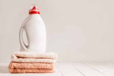 Bir taze renkli havlu duran bir beyaz adlandırılmamış plastik şişe yıkama Çamaşırhane için jel. Beyaz ahşap raf kompozisyonu