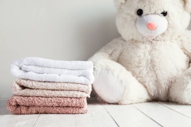 Beyaz ahşap masa arka plan üzerinde beyaz yumuşak oyuncak ayı ile spa havlu yığını. Çocuk çamaşır kavramı