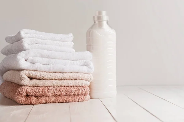 Botella con gel para lavar y una pila de toallas frescas sobre una mesa de madera — Foto de Stock