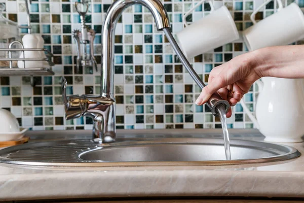 A housewife girl uses a kitchen faucet with a hose for washing dishes. — Stock Photo, Image