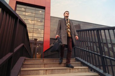 Office modaya uygun genç iş adamı şehirde yürüyüş bir çanta ile giyinmiş