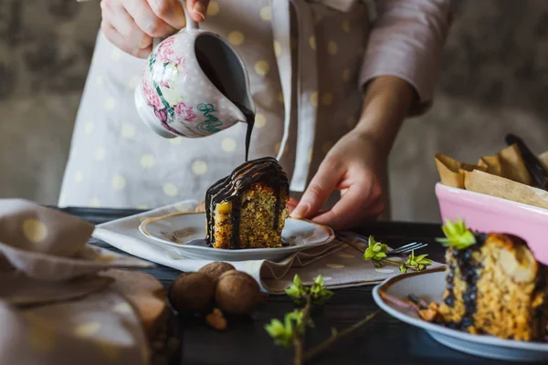 Close-up of the hand of baking girl is pouring chocolate glaze over a mouth-watering piece of cake. — Stock Photo, Image