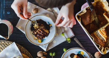 Baker sanatçı kadın sıcak Muzlu Kek, tatma çikolata ile dökülür. Üstten Görünüm. Sanat sofra ile siyah rustik masaya