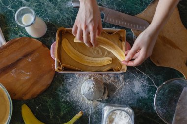 Kız hamur tavayla kesilmiş muz koyar. Üstten Görünüm.