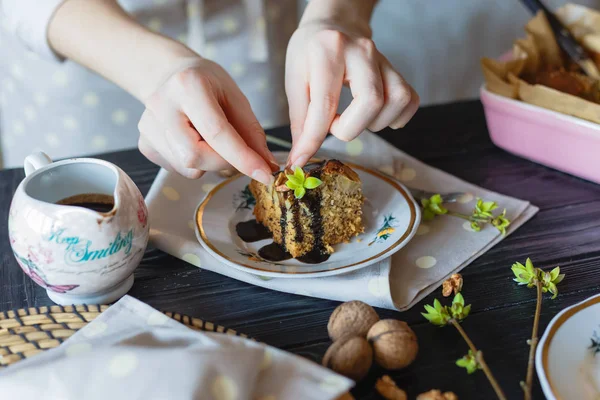 The housewife decorates a piece of cake with walnuts. — Stock Photo, Image