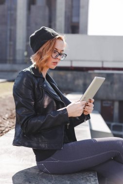 Siyah giyen genç bir kadın şehirde açık tablet kullanma.