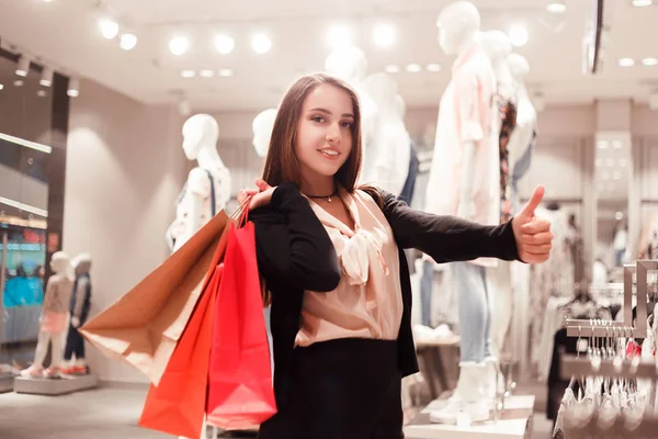 幸せなファッション女性ファッション ブティックでカラフルなショッピング バッグが親指を表示されています。 — ストック写真