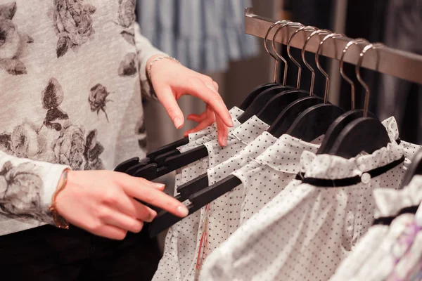 Zblízka žena ruce na ramínka na šaty v obchodě kupovat oblečení. Shopping.Woman se rozhodne, co chce vyzkoušet na — Stock fotografie