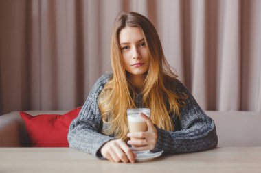 Genç hüzünlü güzel kız kafede kahve içiyor.