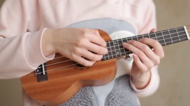 Kız parmak tarafından ukulele üzerinde oynuyor