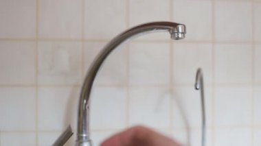 Kapalı mutfak musluk açmak sonra sabit basınç ile akan su adam tarafından.