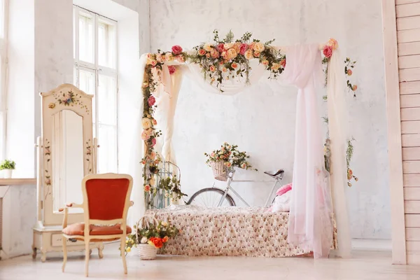 Романтичний інтер'єр спальні. Ліжко з аркою квітів, дзеркало, крісло і ретро велосипед стоїть біля стіни . — стокове фото
