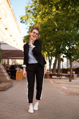 Moda Bayan siyah ceket, mavi bluz ve beyaz spor ayakkabı ile bak. Moda kavramı.