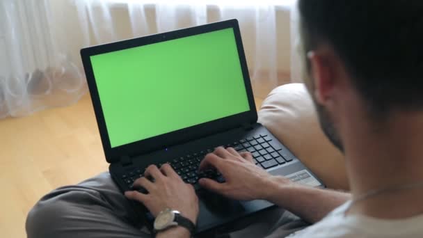 Мужчина использует ноутбук в своем домашнем офисе. Зеленый экран для пользовательского контента — стоковое видео