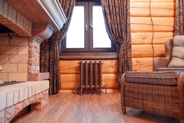 Pencerenin altında dökme demir bir retro radyatör ile ahşap bir evde bir baca salonun iç