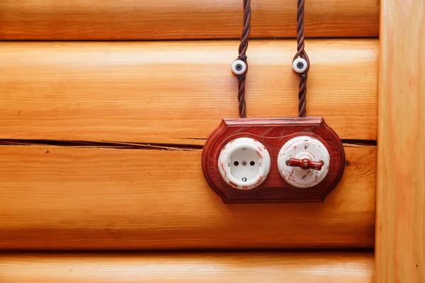 Tomada elétrica e comutador em estilo retro em uma parede de madeira. Projeto de eletricistas na casa . — Fotografia de Stock