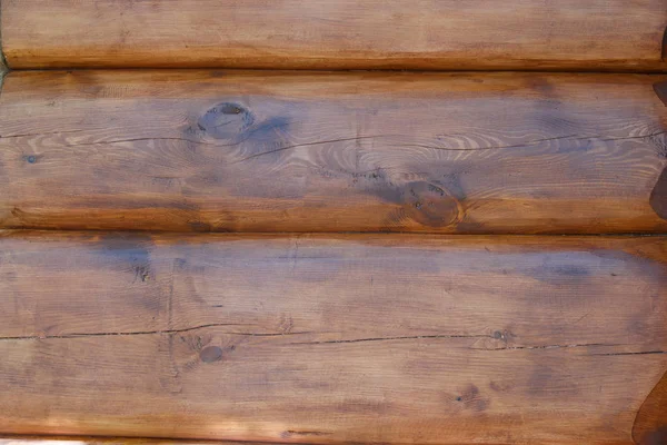 La textura de la pared de la casa está hecha de troncos redondos, cubiertos con impregnación protectora. De cerca. —  Fotos de Stock