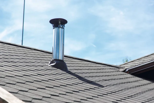 Schoorsteenpijp van roestvrij staal op het dak van het huis. — Stockfoto