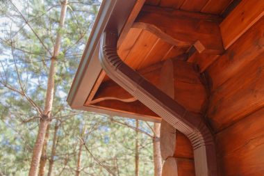 Roof gutter system on log house in forest clipart