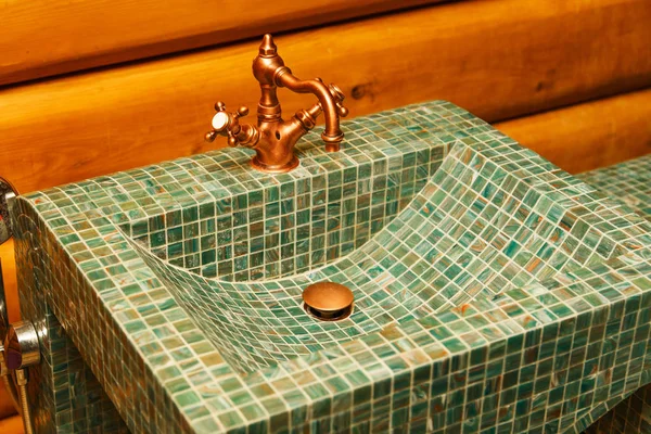 El grifo de cobre en un lavabo hecho de azulejo de mosaico verde . — Foto de Stock